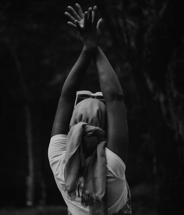 Woman in a calm yoga pose against a dark background with cyan highlights.